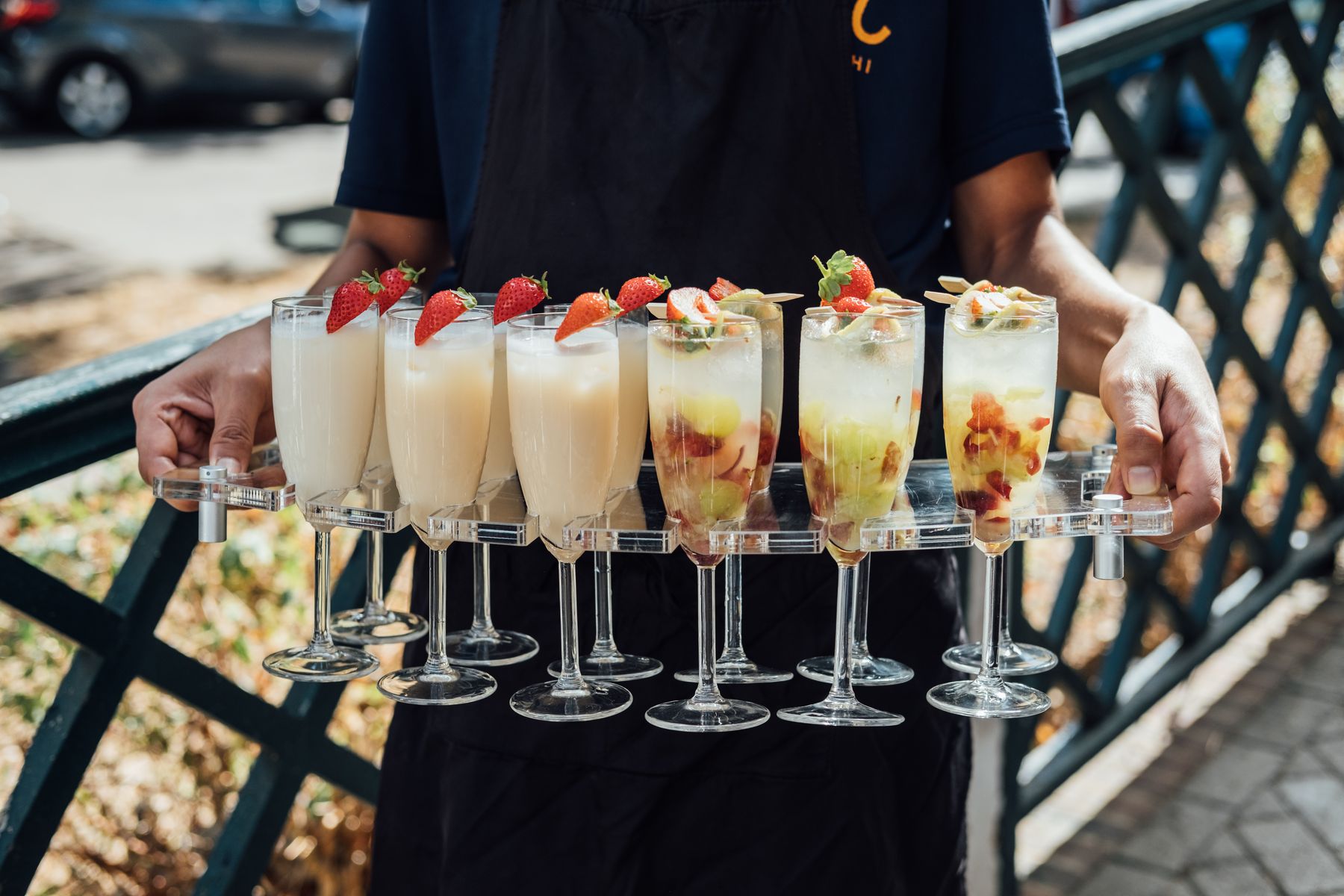 Staff carrying a tray of garnished drinks beside railings